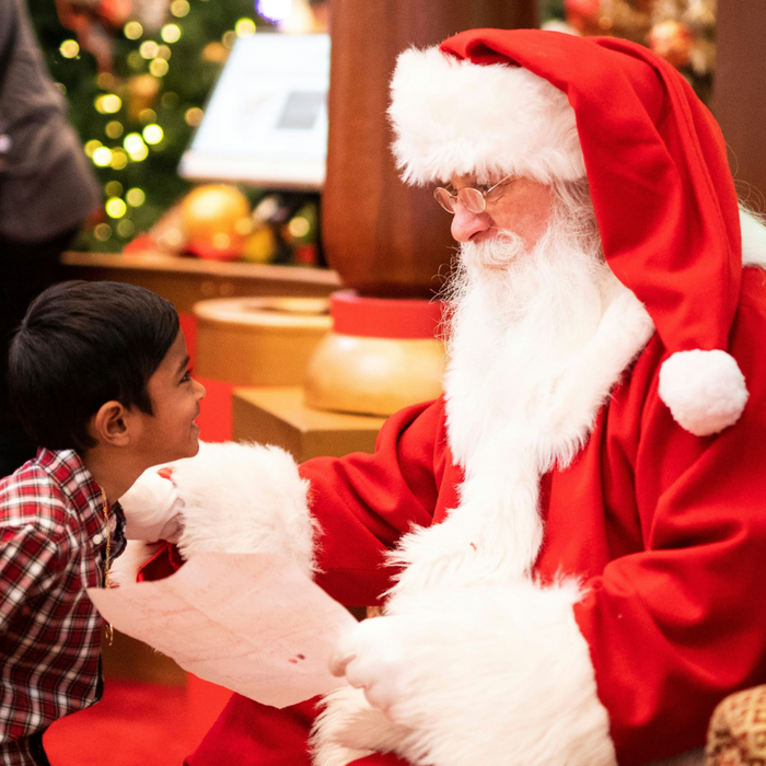 Child leaning towards a man dressed as santa in a cosy setting