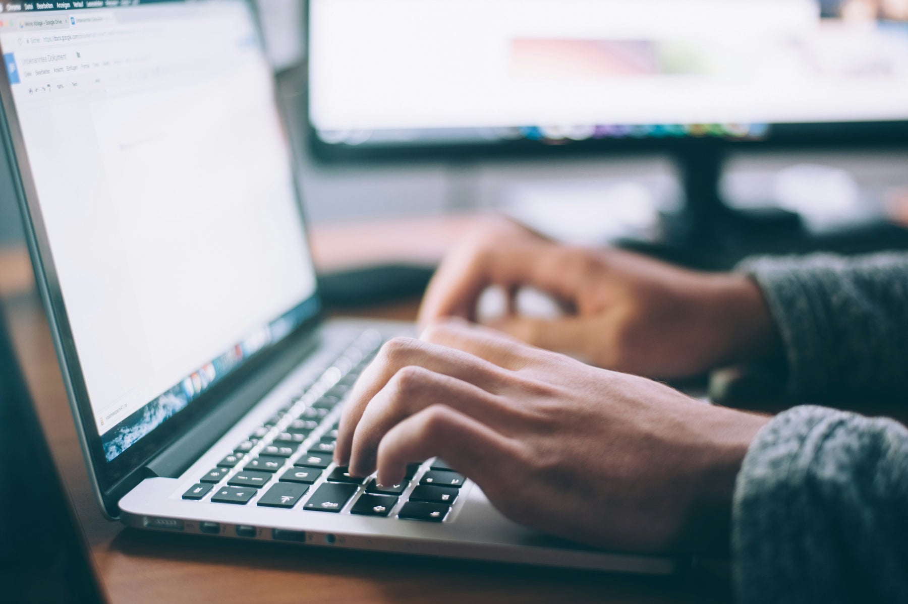 image of a laptop with a pair of hands typing 