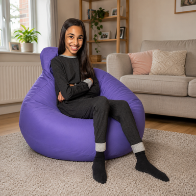 A young woman sitting in a purple bean bag chair in a cozy living room setting.